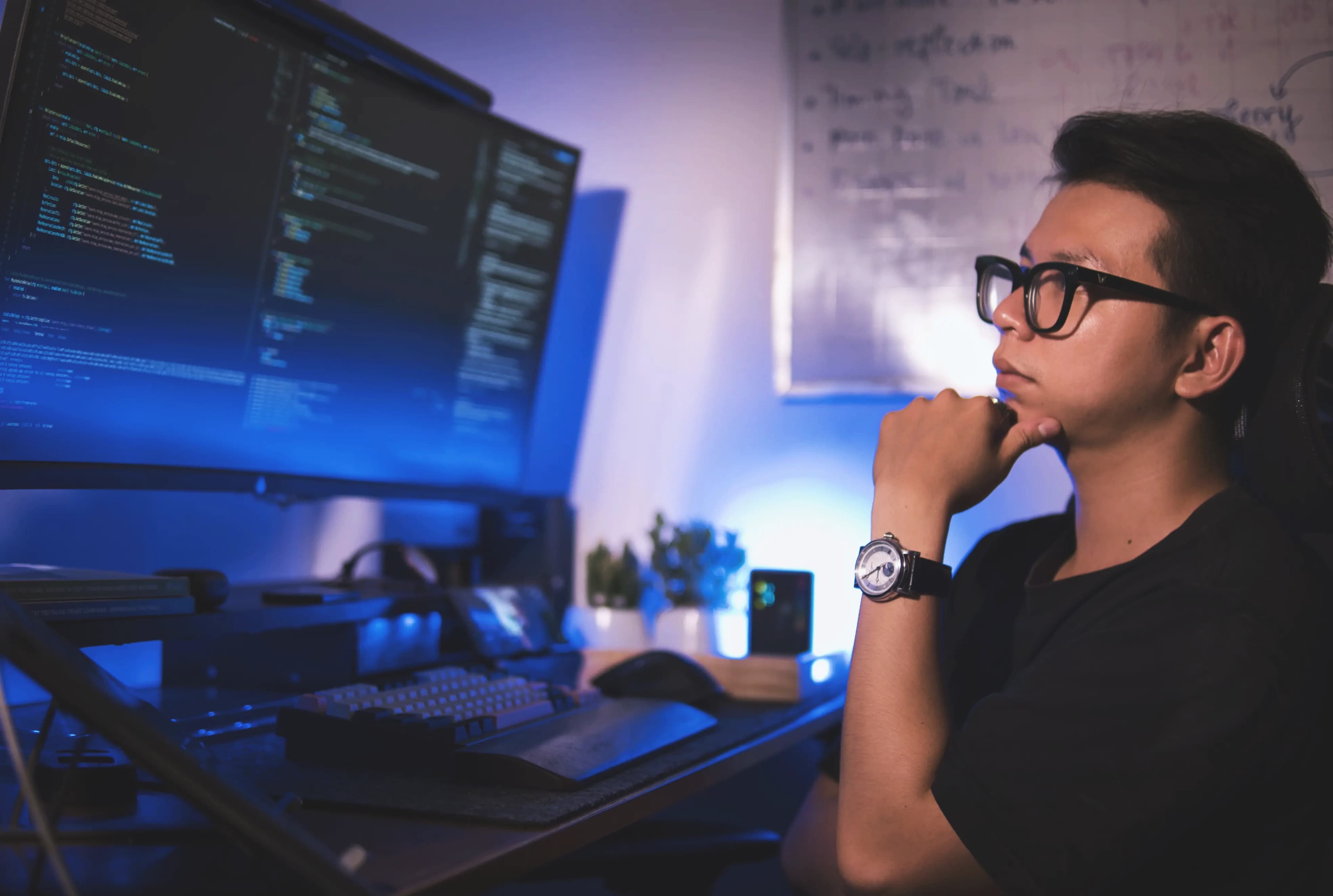 Thanh working at a desk with code displayed across two monitors